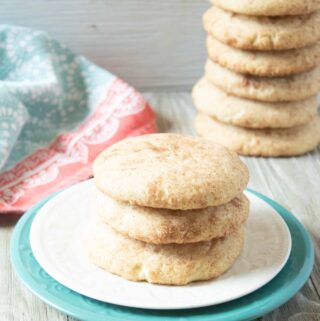 stack of snickerdoodles on white and teal plates, with a huge stack of cookies in the background