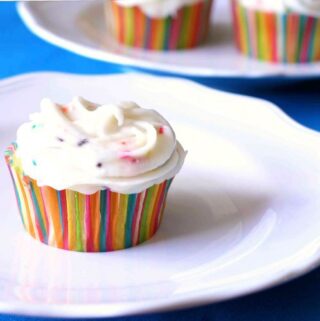 a lemon cupcake with a colorful cupcake liner sitting on a white plate