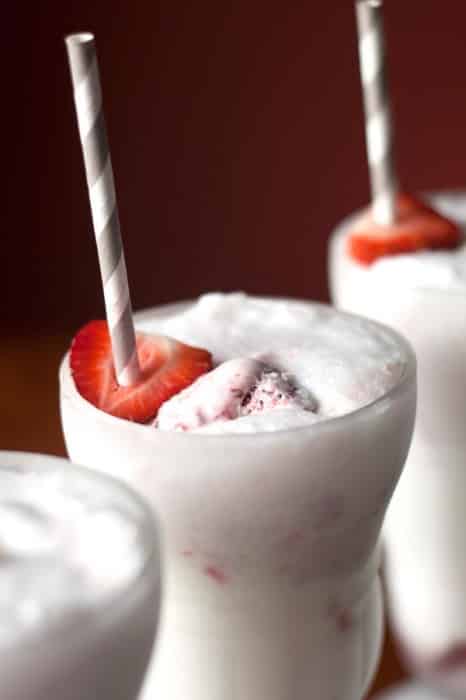 closeup of a Strawberry Ice Cream Soda with a straw sticking through a fresh strawberry