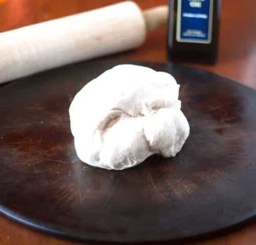 dough for pizza calzones rolled in a ball and on a dark wooden circle