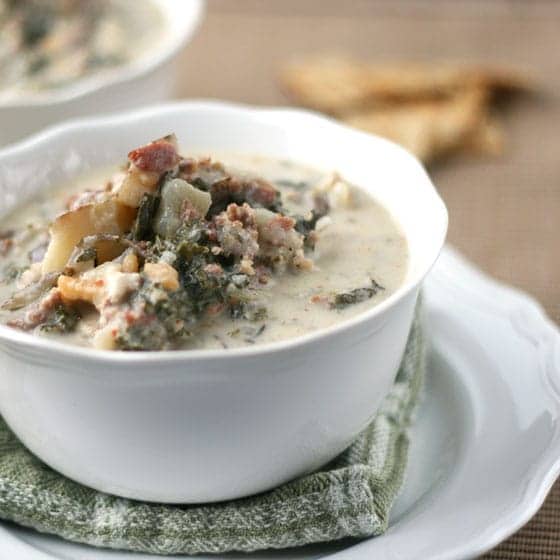 zuppa toscana in white bowl sitting on green towel and white plate