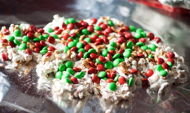 White chocolate and crushed pretzels topped with red and green M&Ms setting on foil