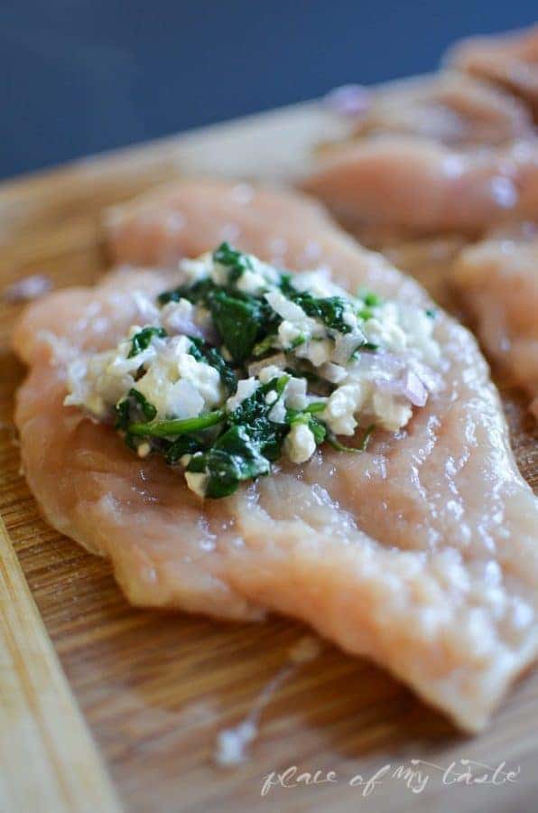 Spinach, onion and feta filling spooned onto a flattened raw chicken breast before rolling