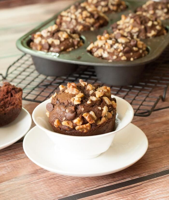 Chocolate chocolate chip banana nut muffin with walnut and chocolate chip topping in a white cup