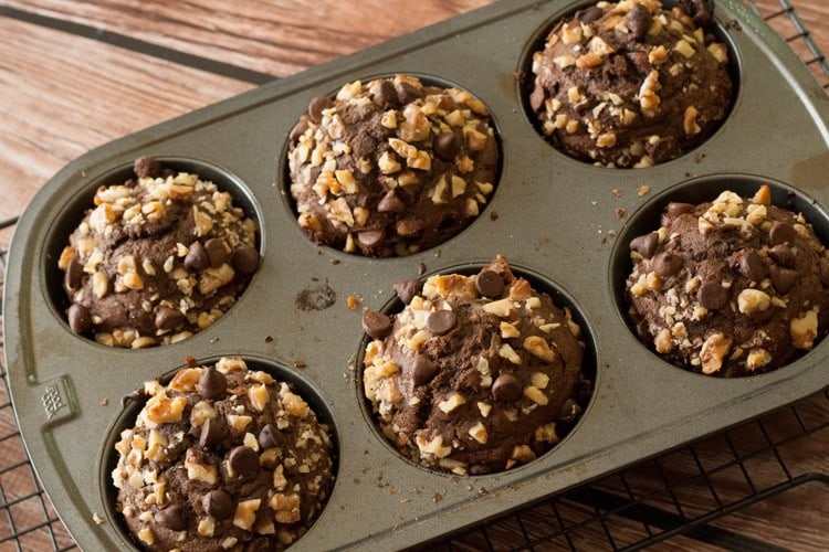Jumbo chocolate chocolate chip banana nut muffins topped with walnuts in a six-cup muffin pan