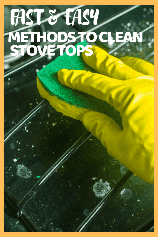 gloved hand holding a scouring pad and cleaning the grate of a green gas stove top
