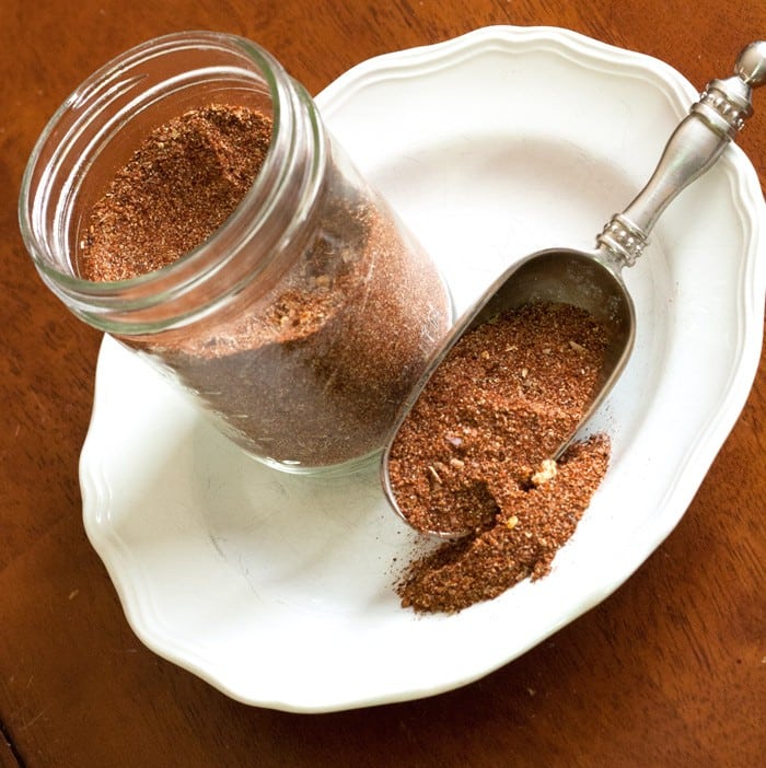 DIY Taco Seasoning in a ball canning jar on a white plate next to a scoop