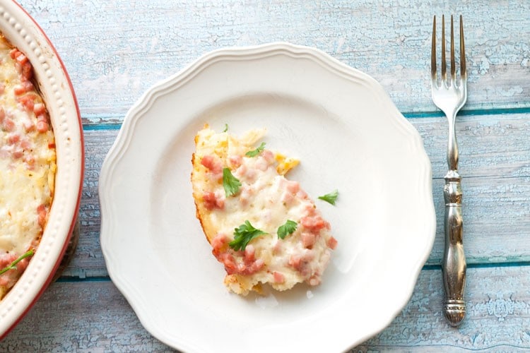 Slice of southwest breakfast casserole on a white plate with a fork