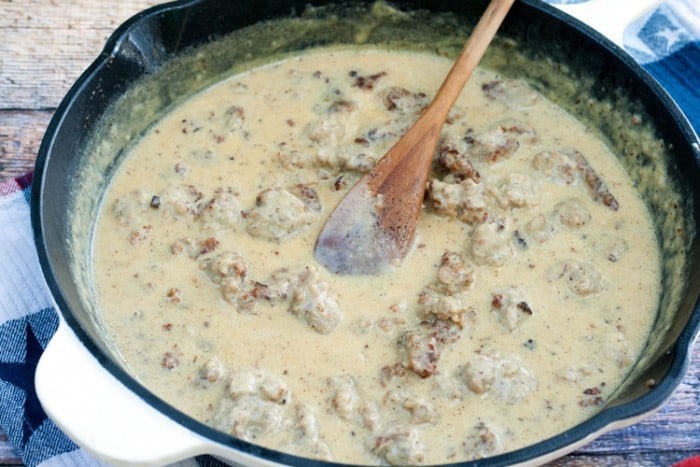 homemade sausage gravy being stirred in the pan