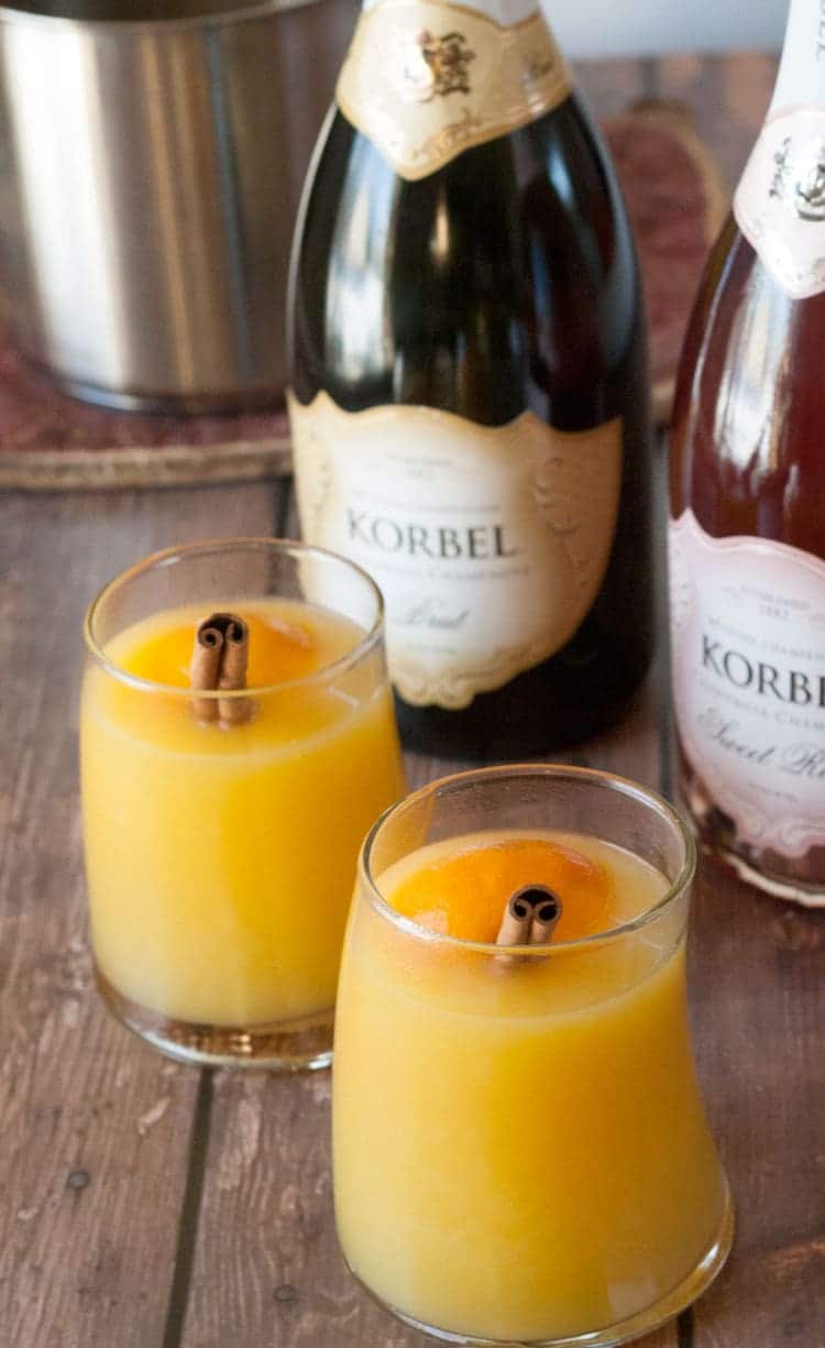 Warm mulled mimosa cocktails served next to a slow cooker for holiday brunch