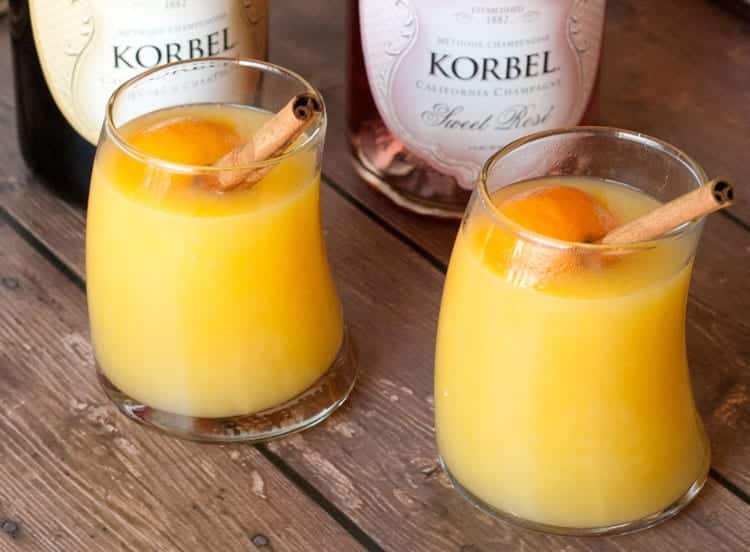 Close-up of warm mulled mimosa glasses garnished with orange and cinnamon sticks