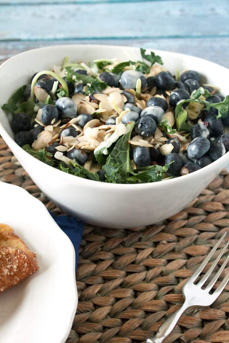 kale salad with blueberries and almonds in white bowl