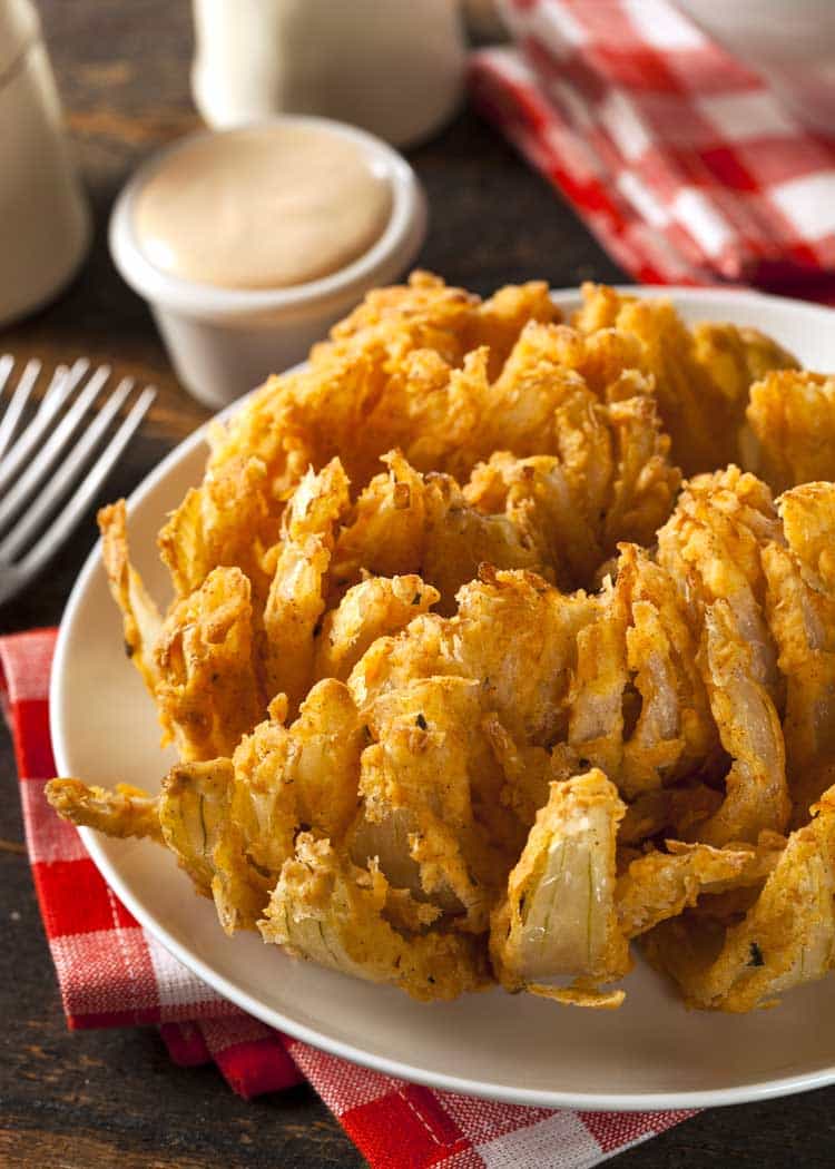 blooming onion on white plate with red gingham napkins