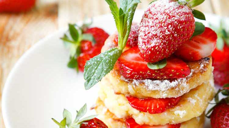 pancakes with strawberries and mint on white plate