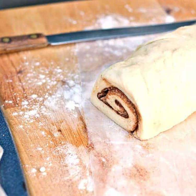 cinnamon roll dough on cutting board ready to be cut