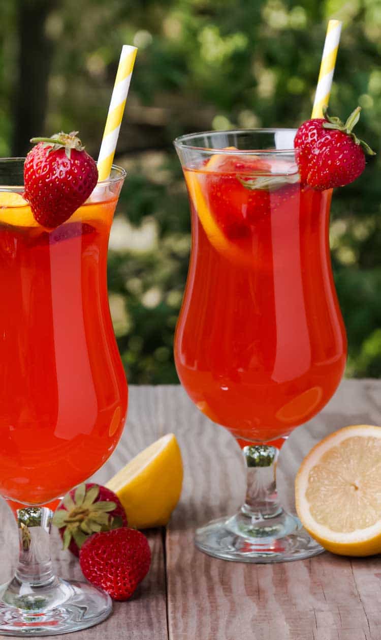 two hurricane glasses with strawberry lemonade and paper straws