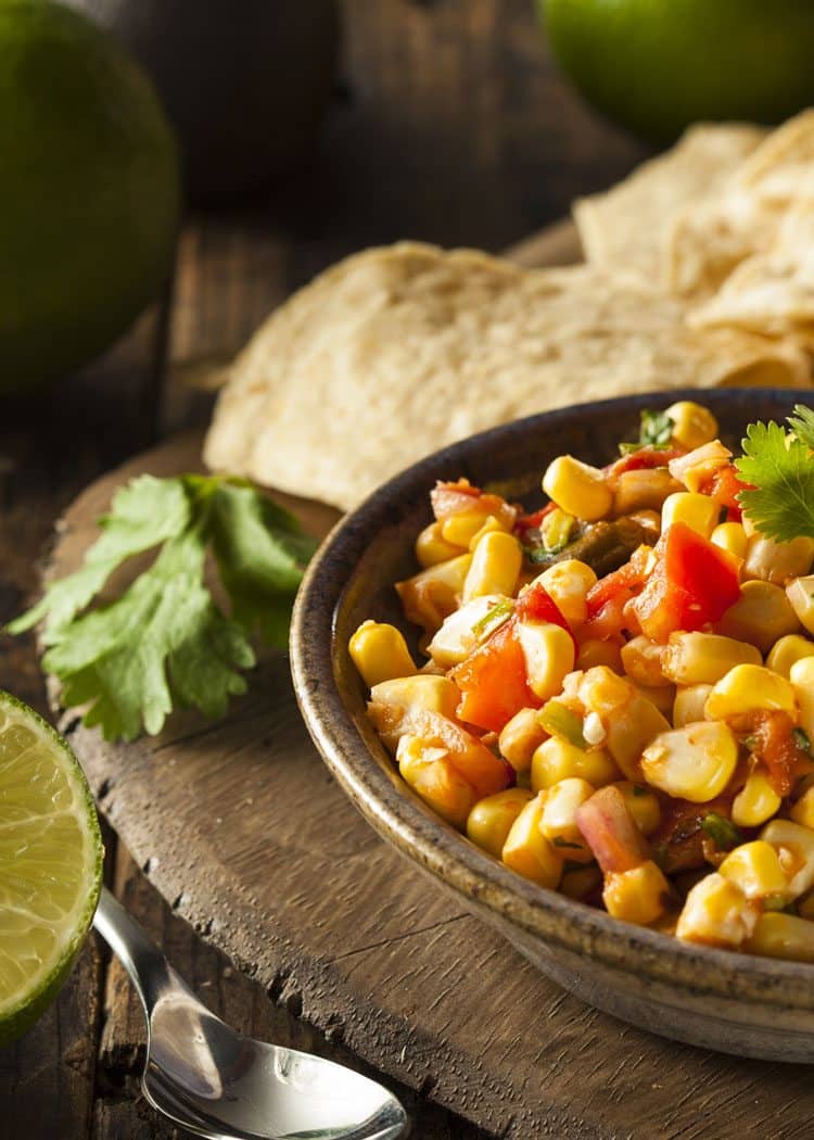 corn salsa with limes on rustic wood table