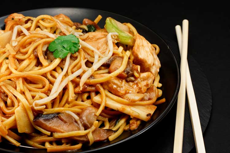 chow mein noodles on black plate with chopsticks