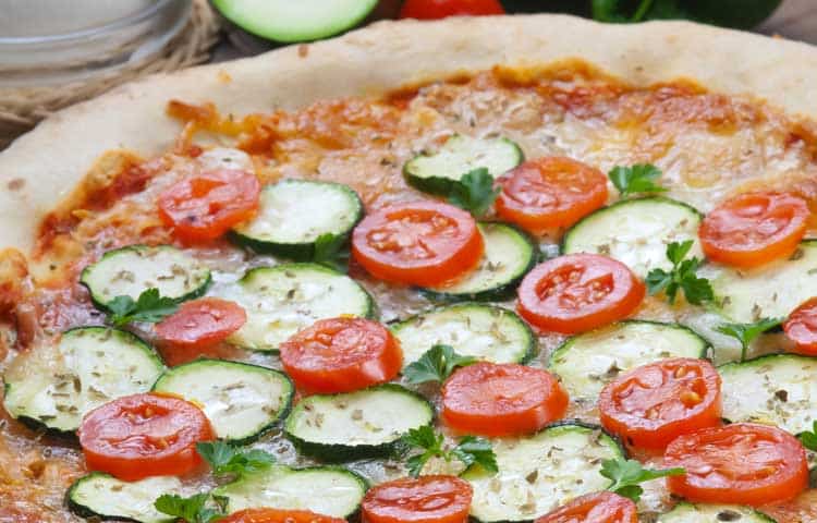 vegetarian pizza with zucchini and tomatoes on table