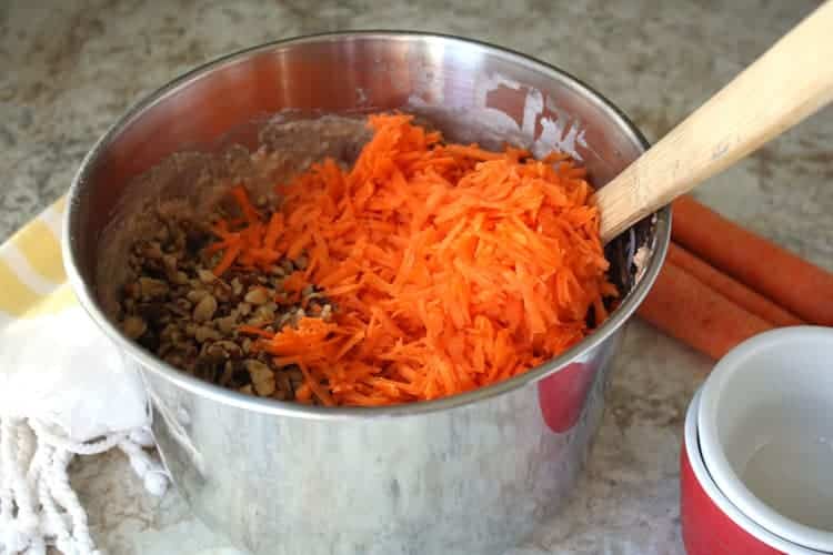 stainless steel bowl containing batter with shredded carrots on top for best carrot cake recipe