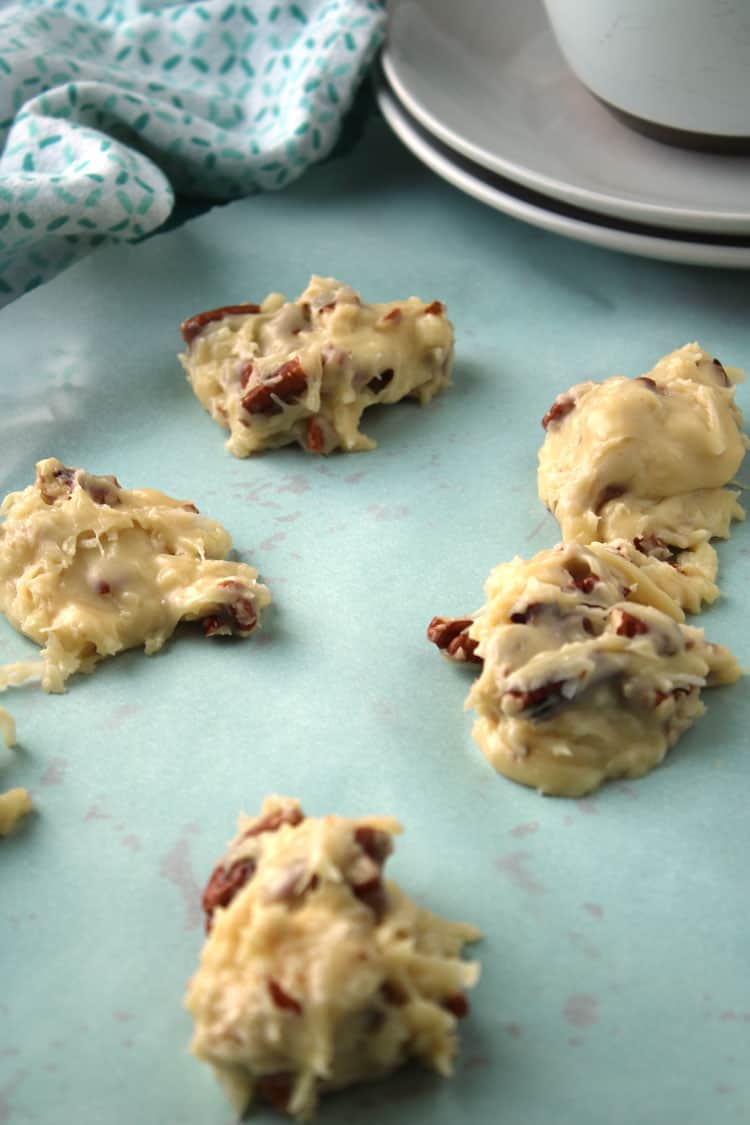 closeup of coconut clusters on a blue plate waiting to cool with blue and white towel and grey saucers in background