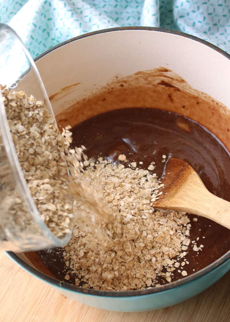 no bake chocolate oatmeal cookies batter with oatmeal being stirred in with a wooden spoon