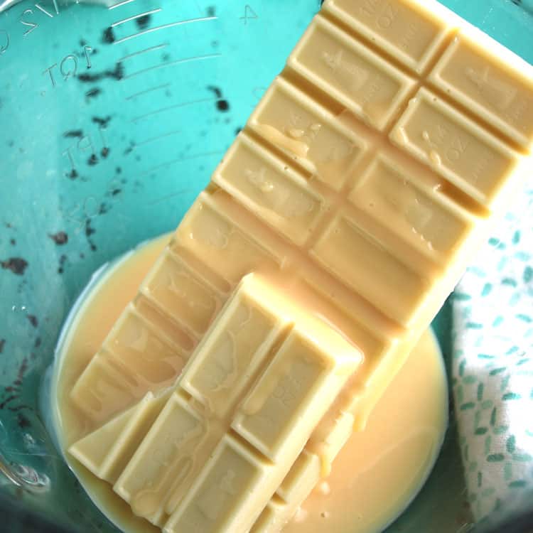 measuring cup with bars of white chocolate melting to be used in coconut clusters