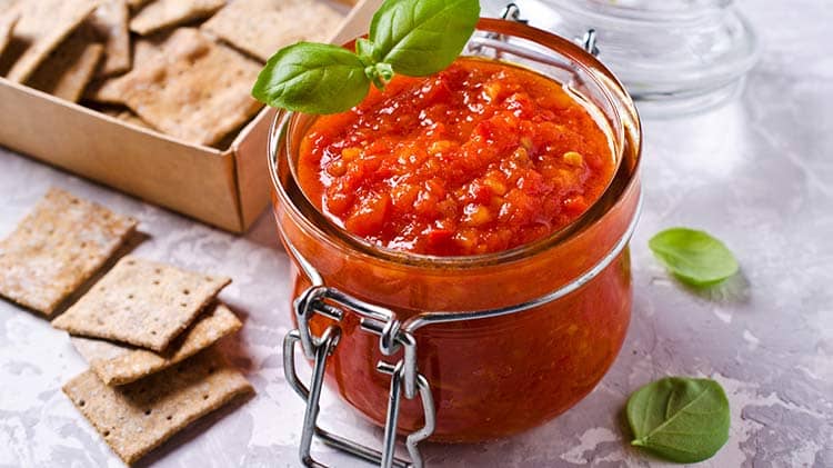 canned crushed tomatoes in a glass jar with crackers