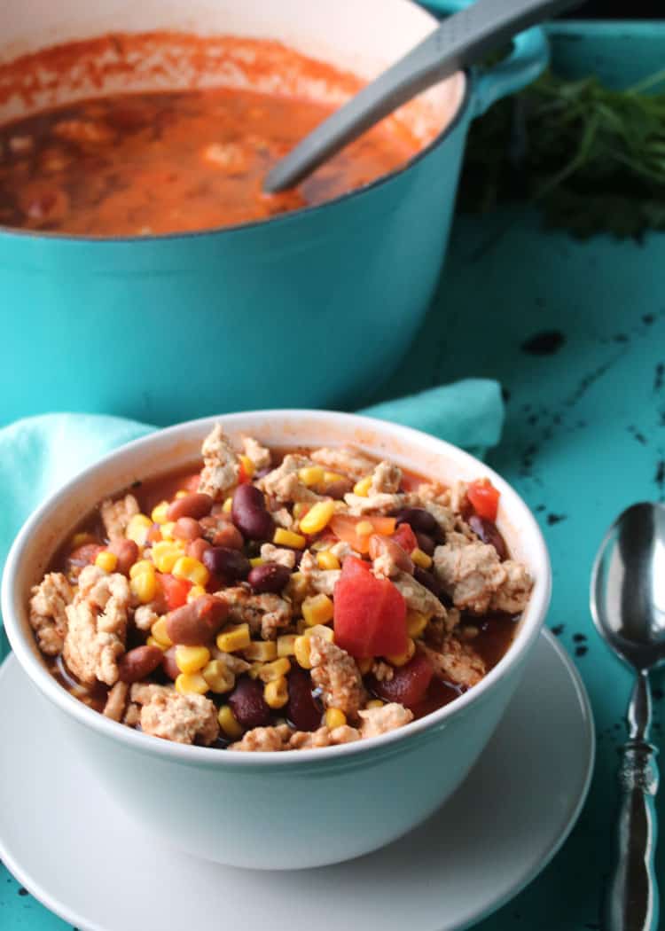 Weight Watchers taco soup served in a white bowl with a spoon on a turquoise table