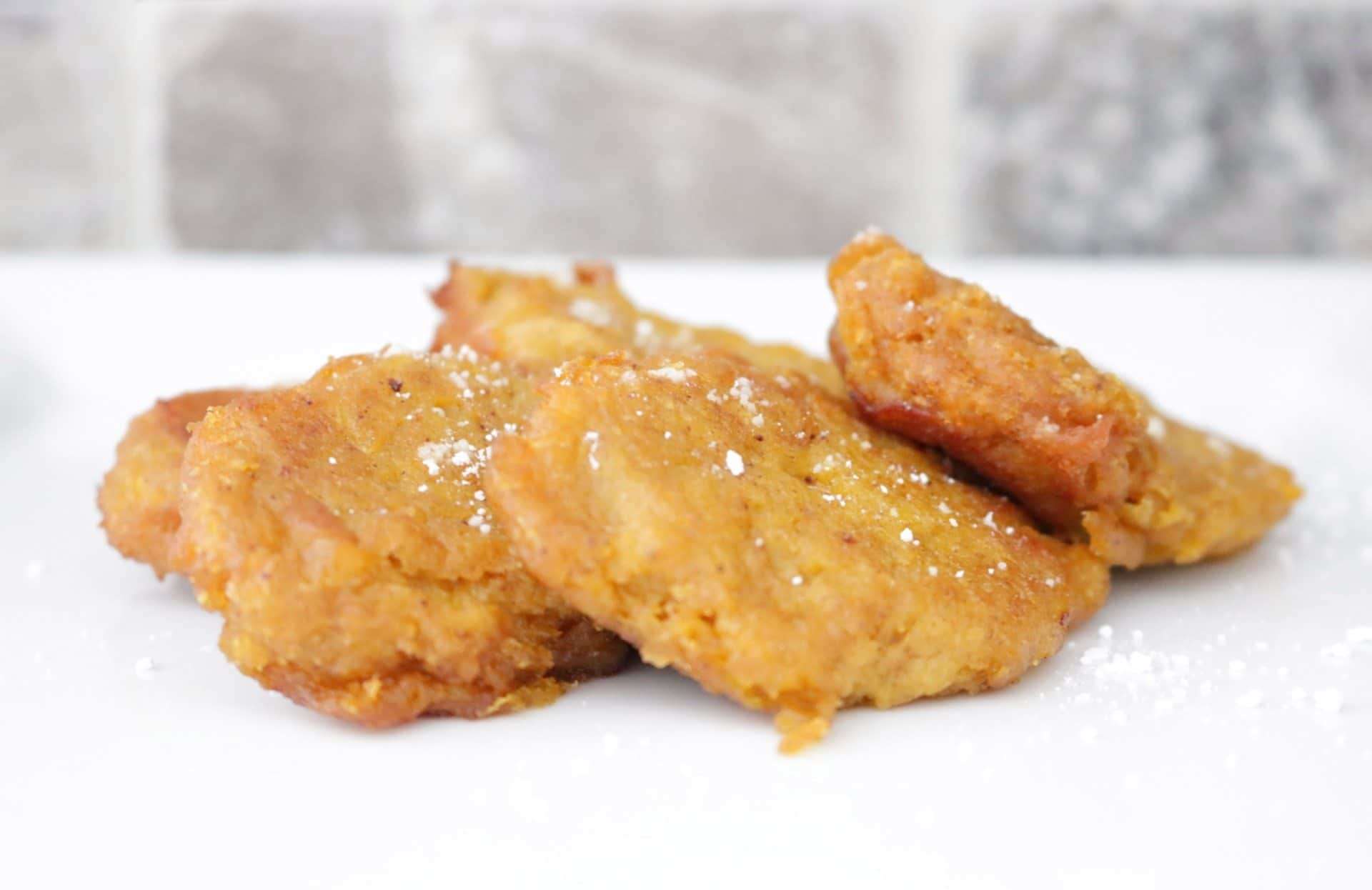 Side view of crispy fried pumpkin patties sprinkled with powdered sugar