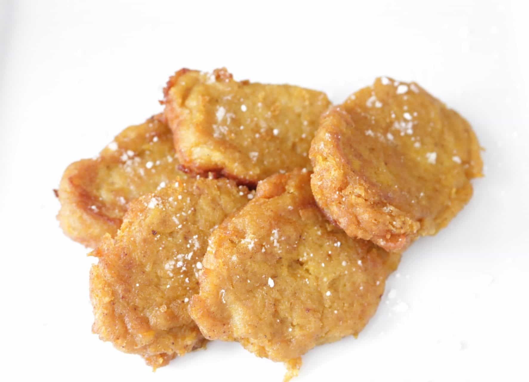 Overhead view of homemade pumpkin patties dusted with powdered sugar on a white plate