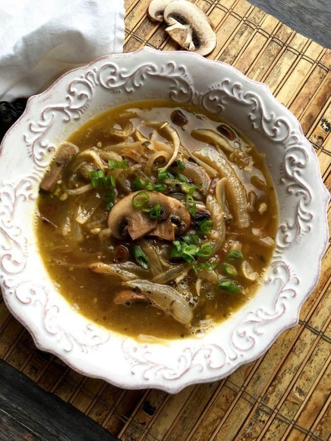 Daikon noodle soup with mushrooms, caramelized onions and green onions in a white bowl