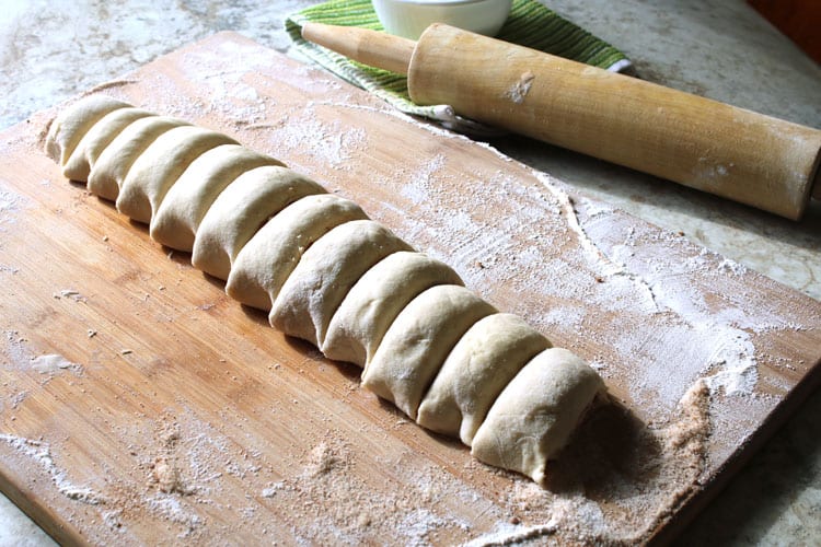 homemade cinnamon rolls raw dough sliced on top of floured surface