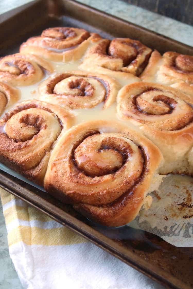 baked homemade cinnamon rolls freshly out of oven on pan with one homemade cinnamon roll missing