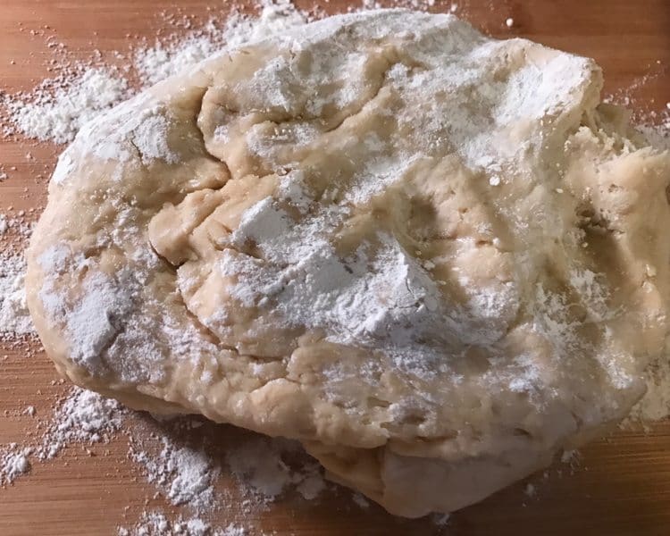 easy yeast rolls dough sitting on cutting board with flour sprinkled on top