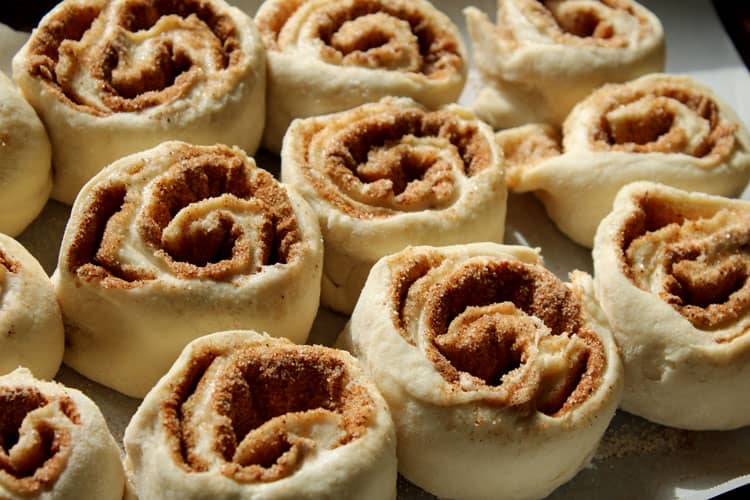 raw homemade cinnamon rolls sitting on pan while rising