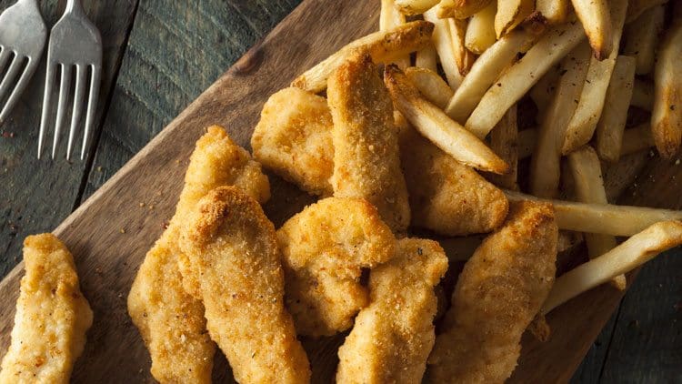 chicken strips and french fries on wood plank board