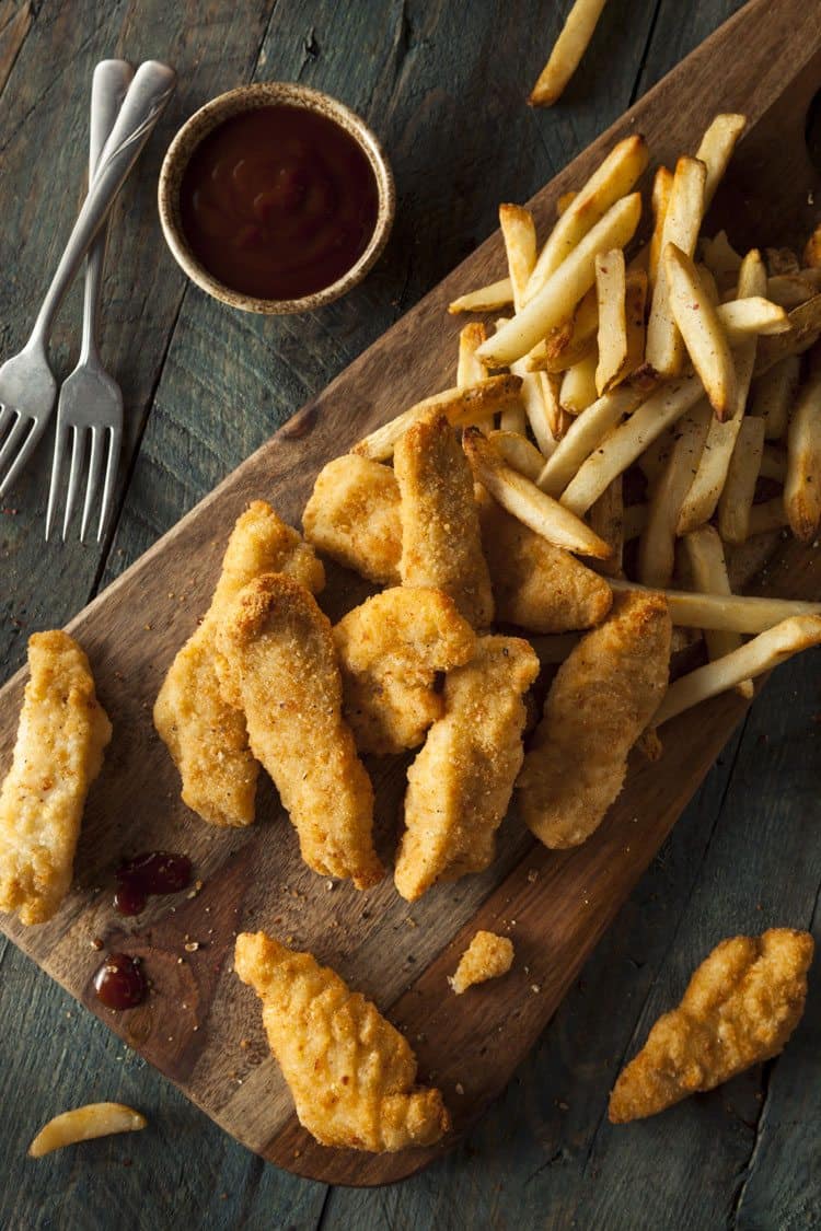 chicken strips and french fries on wood plank board