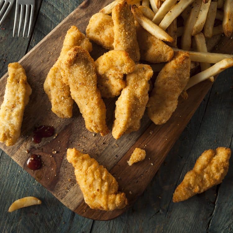 chicken strips and french fries on wood plank board