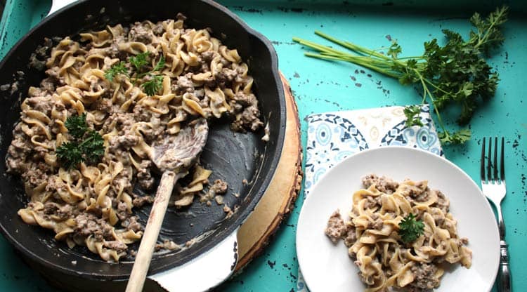 weight watchers beef stroganoff in cast iron pan with a white plate of stroganoff off to the side