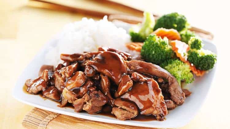 bourbon street chicken with rice and broccoli on white plate