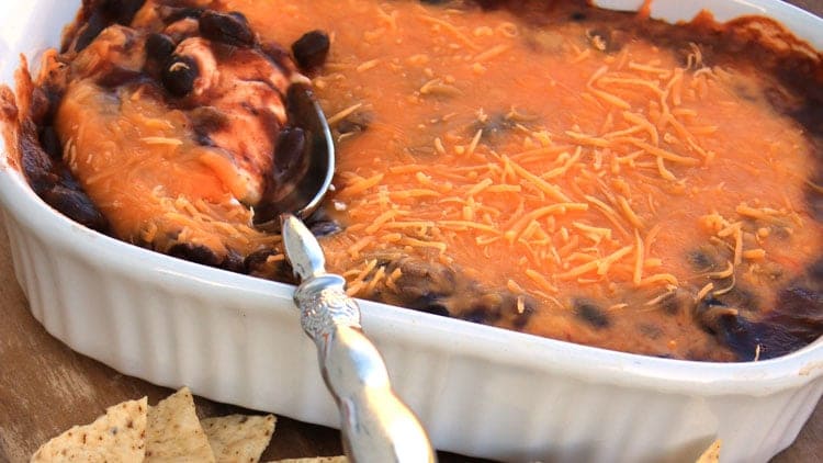 chili cheese dip being scooped from a white casserole dish