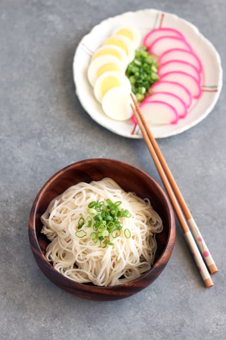 cold somen noodles being served in a wooden bowl with chopsticks
