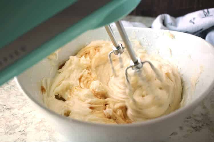 closeup of finished easy cream cheese frosting being beaten on low speed by a mixer