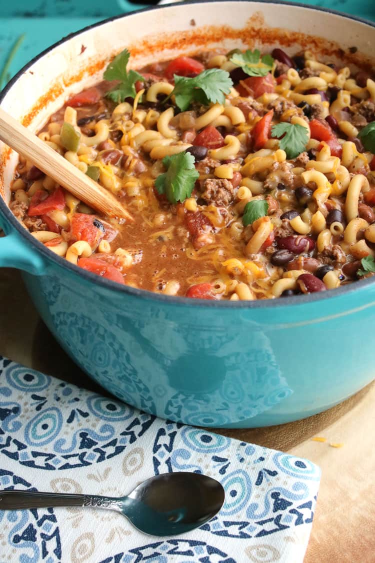 chili mac and cheese being served from a large blue stock pot