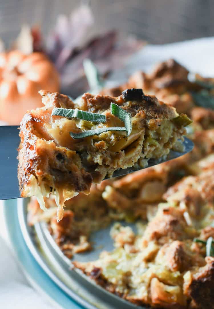 serving a slice of the savory bread pudding with apples and herbs