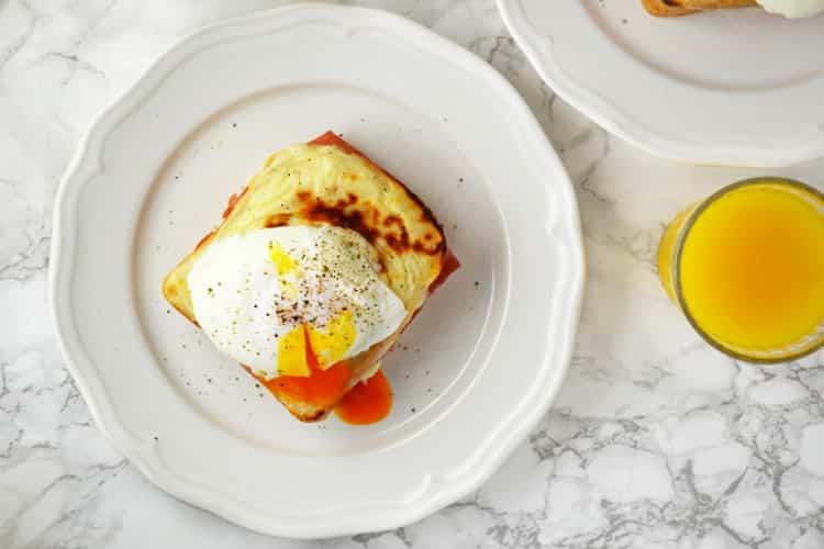 Easy croque madame with a glass of orange juice on marble surface