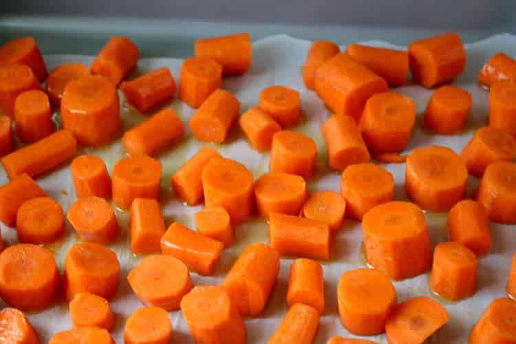 carrots coated in olive oil on baking sheet lined with parchment paper