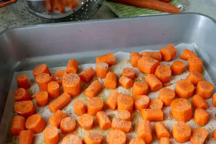 chunks of carrot coated in olive oil in roasting pan
