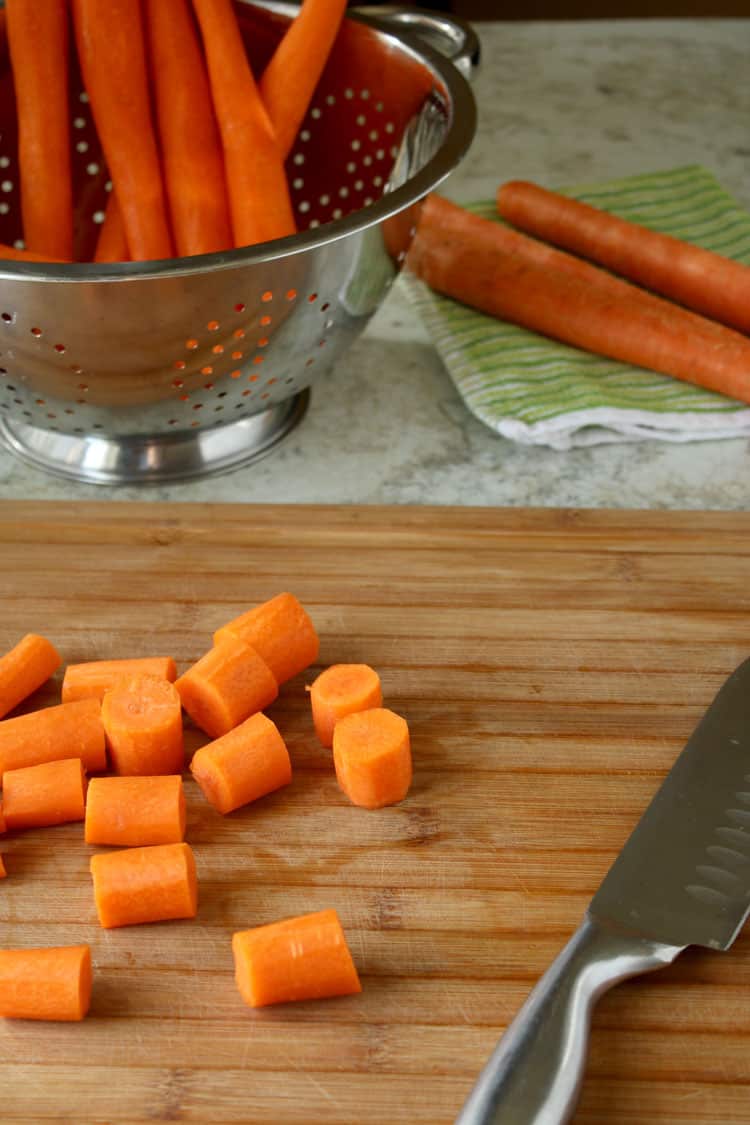 chopped carrots with knife on a wood cutting board